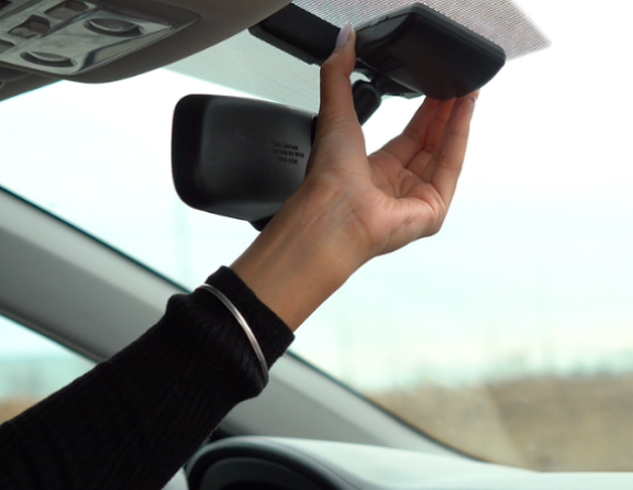 A person sticks their transponder to the inside of their front windshield.